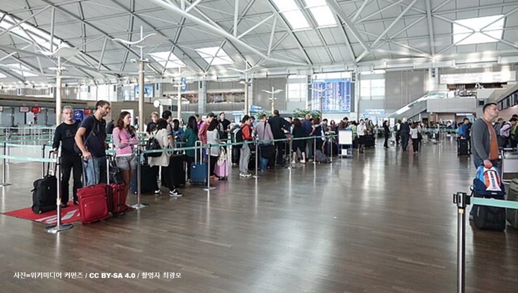 인천국제공항 터미널에서 수하물을 부치기 위해 길게 줄을 서서 대기하고 있는 여행객들의 모습과 중동발 항공 운임 폭등 및 유류할증료 인상 관련 글로벌 경제 보도 이미지 (출처: 촬영자 최광모 / 위키미디어 커먼즈)