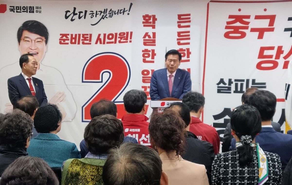 송해선 시의원 후보의 개소식에 참석한 류규하 대구 중구청장 후보가 연단에 서서 축사를 하고 있는 모습. 뒤편에는 '단디 하겠습니다!', '확실한 일꾼' 등의 선거 문구가 적힌 현수막이 걸려 있고, 많은 지역민이 경청하고 있다.